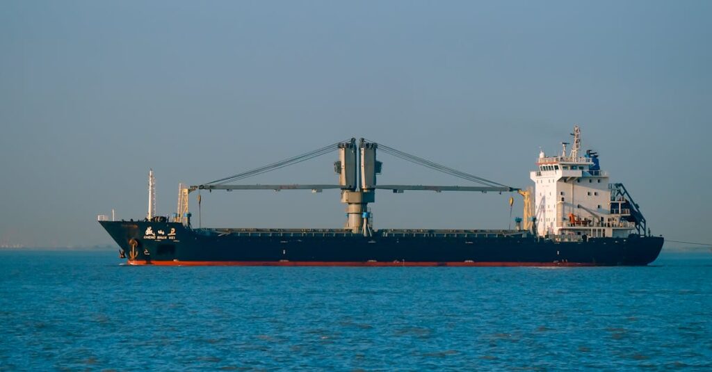 A majestic cargo ship sails across a calm blue sea beneath a clear sky.